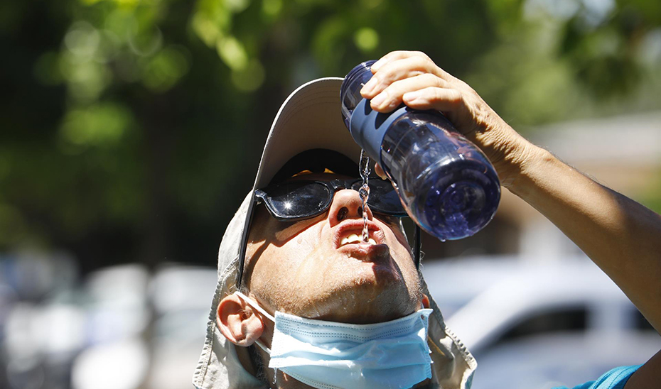 Un hombre se baja la mascarilla para beber agua de una botella (Agencia EFE / Salas)
